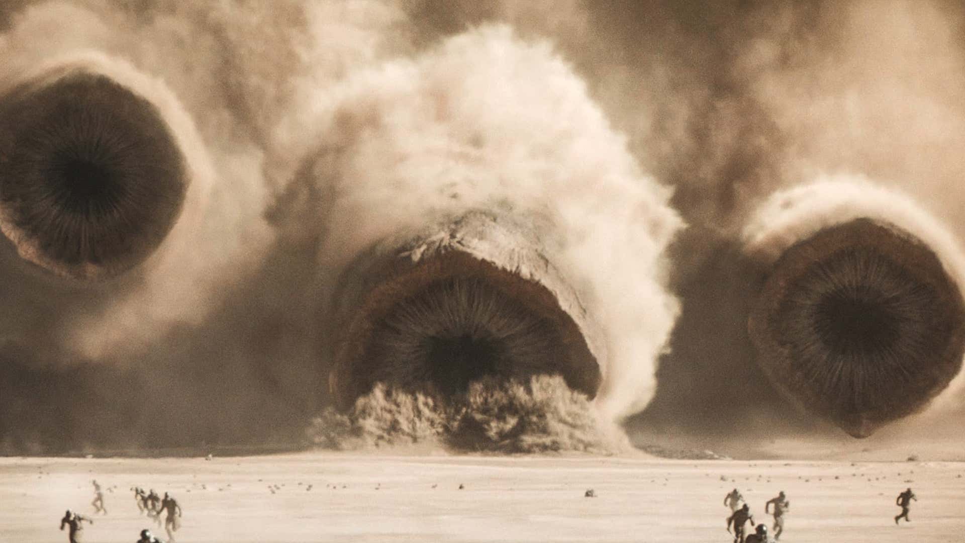 Several sandworms rushed towards the people running on the sand.